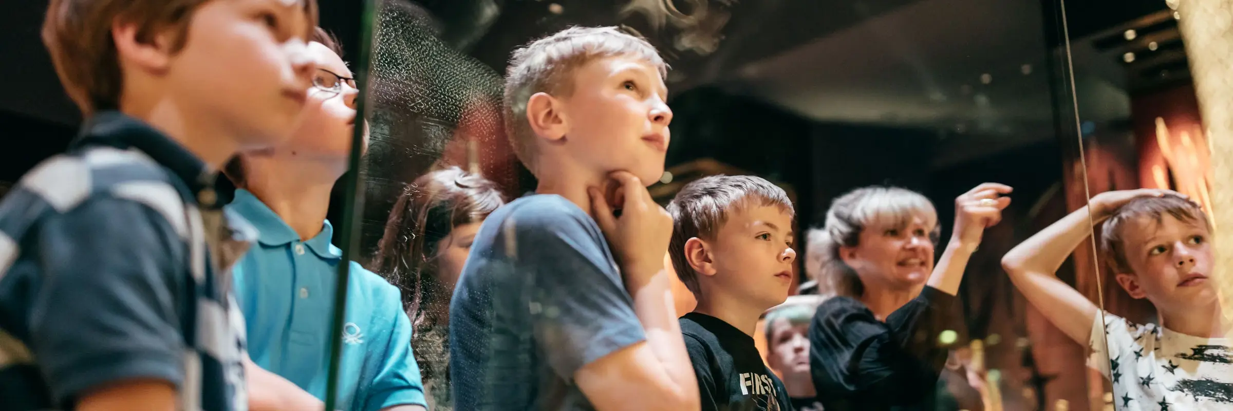 Eine Kindergruppe stehen vor einem Museumsexponat 