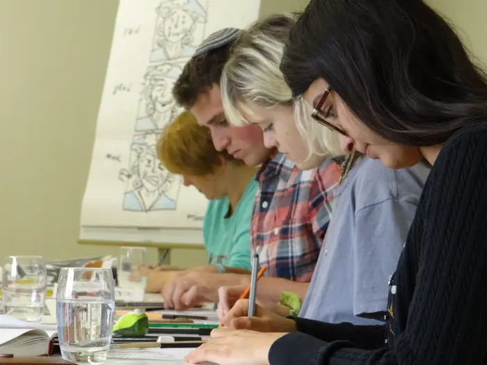 mehrere Personen zeichnen an einem Tisch