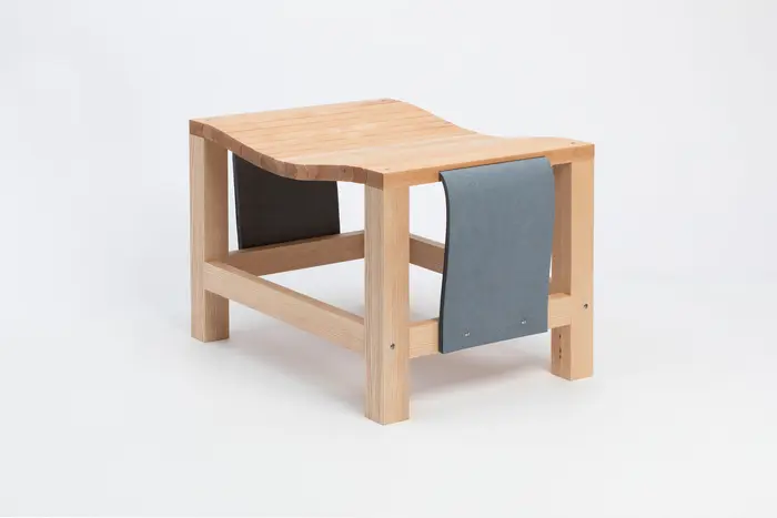 Ein hölzerner Hocker mit grauen Seitenteilen