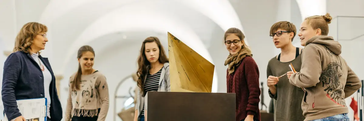 eine Gruppe Jugendlicher betrachtet eine geometrische Skulptur