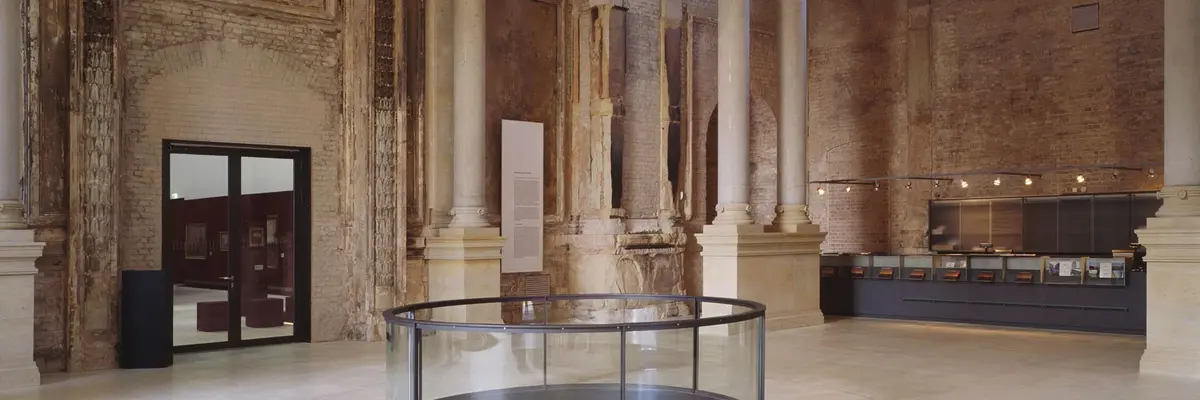 Gemäuer und Säulen, mittig im Raum ein kreisförmiges Geländer