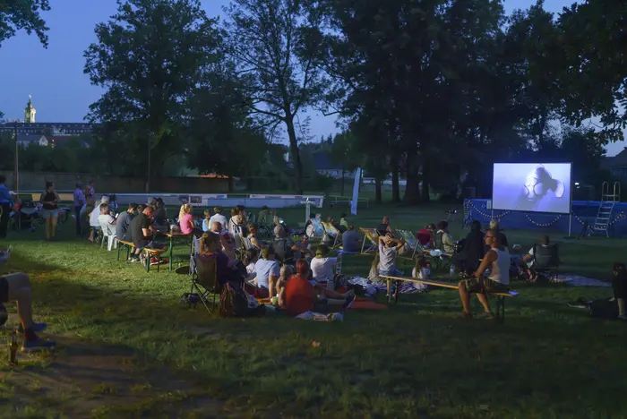 Menschen sitzen im Freien und schauen auf Bildschirm