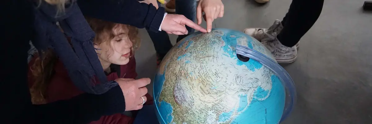 Kinder zeigen auf einen Globus