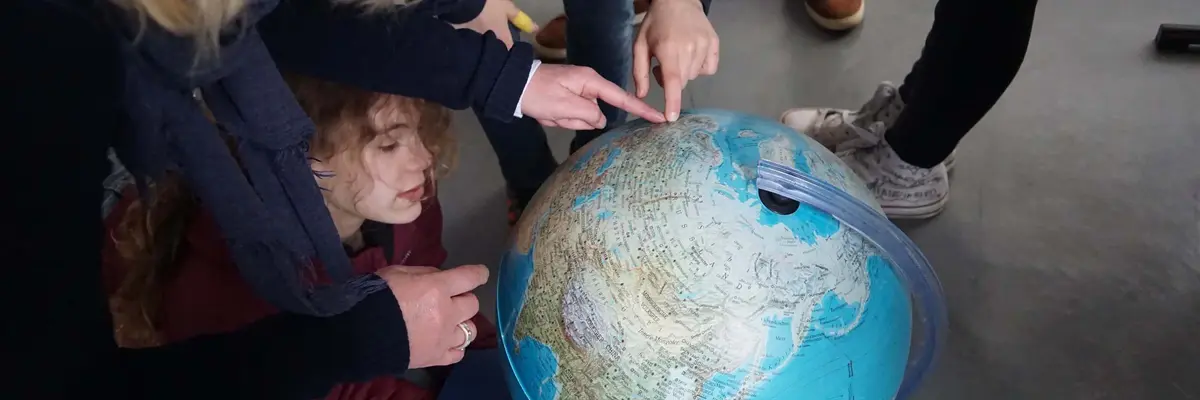 Kinder zeigen auf einen Globus