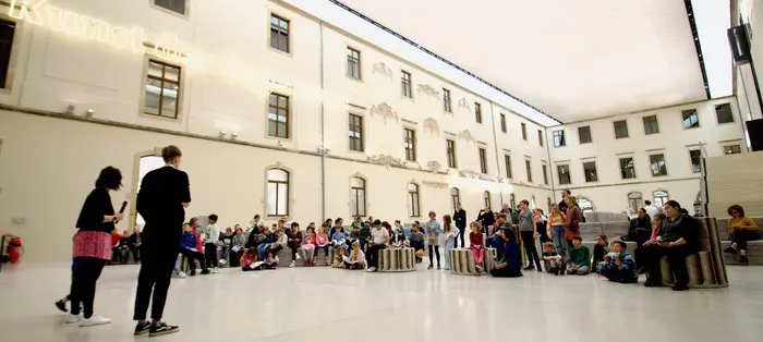 viele Kinder sitzen verteilt im Lichthof im Albertinum und lauschen aufmerksam einem Vortrag