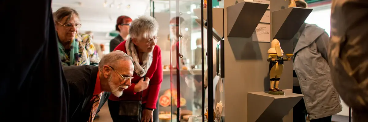 Besucher betrachten kleine Holzfiguren