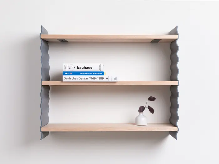 Ein Wandregal mit drei Büchern und einer Vase