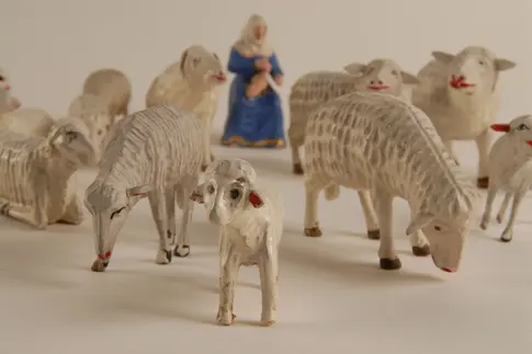 eine Schafherde und eine Figur mit Gewand und Kopftuch
