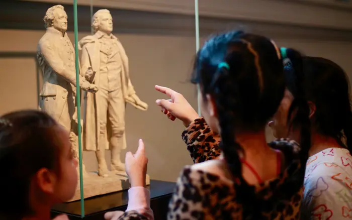 Kinder schauen eine kleine Statue von Schiller und Goethe in einer Vitrine an