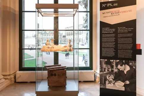 Ausstellungsvitrine mit einer alten Holzkiste und historischen Porzellanvasen