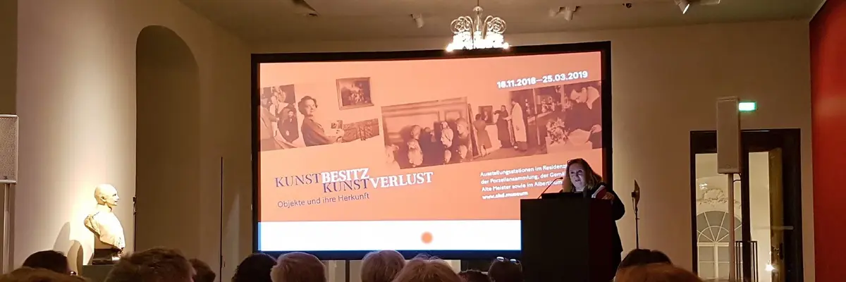 Raum mit einem großen Bildschirm zur Präsentation und sitzenden Personen