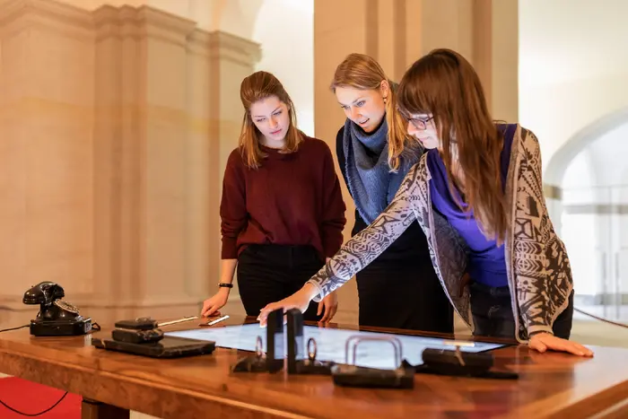 drei Personen benutzen einen Touchscreen in einer Ausstellung